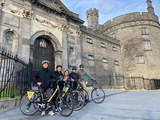 people on bikes in front of stone castle