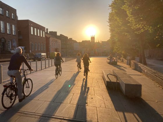 people riding bikes on street while sun setting
