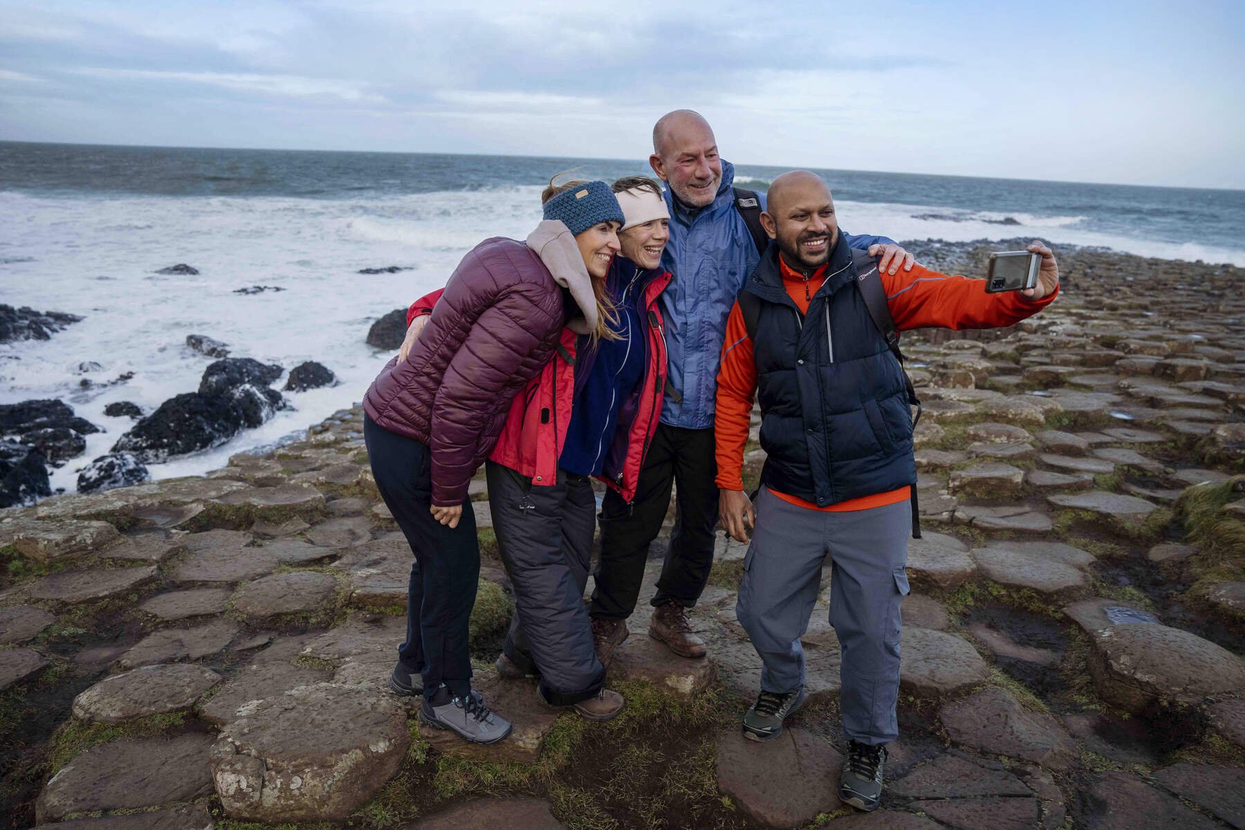 four people standing on rocky landscape while taking photo