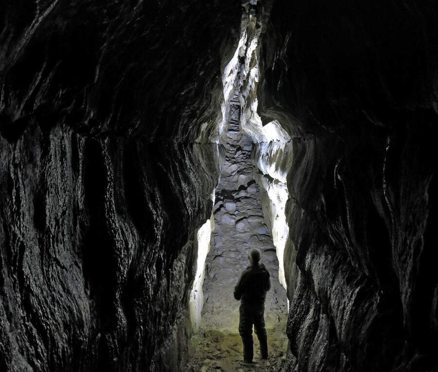 a man standing in the opening of a dark cave